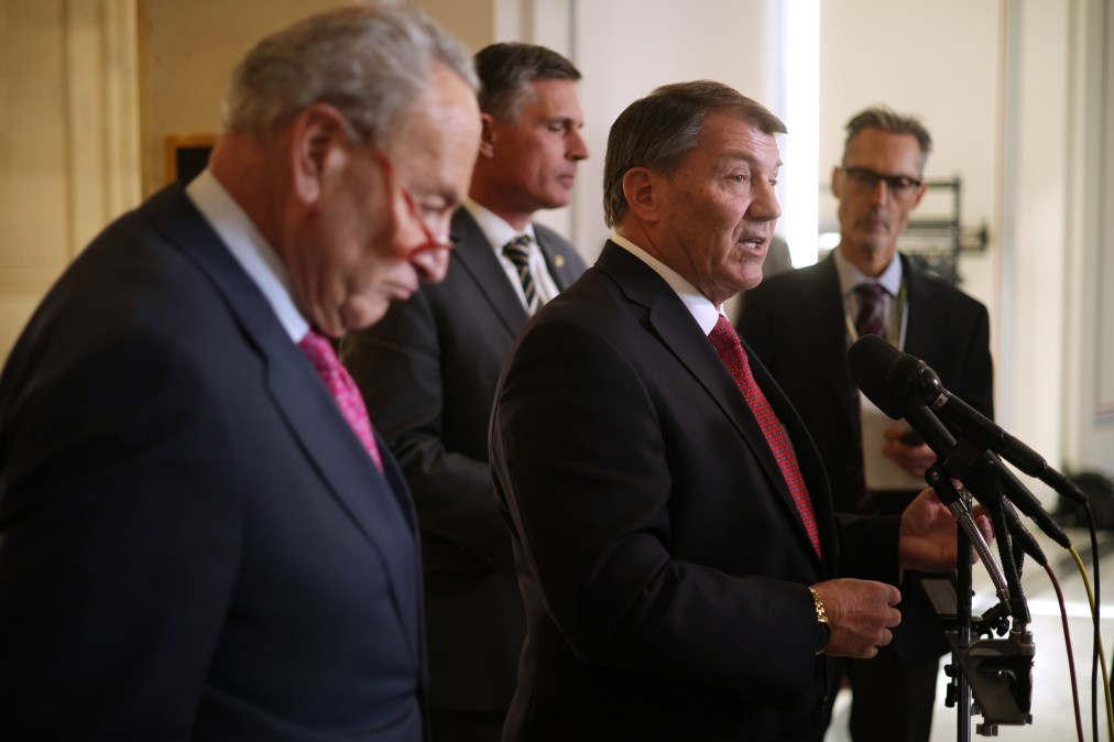 Sen. Mike Rounds, R-S.D., speaks at a microphone as Senate Minority Leader Sen. Chuck Schumer, D-N.Y., and Sen. Martin Heinrich, D-N.M., listen after an AI Insight Forum in November 2023.