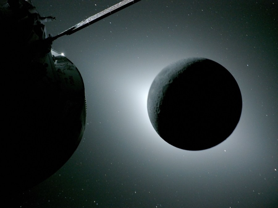 The Moon appears dark in the picture as white sunlight leaks out around its edges. A portion of the Orion spaceship, also in shadow, is visible on the left of the image.